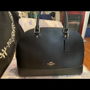 Coach black leather bowler bag with crossbody strap.